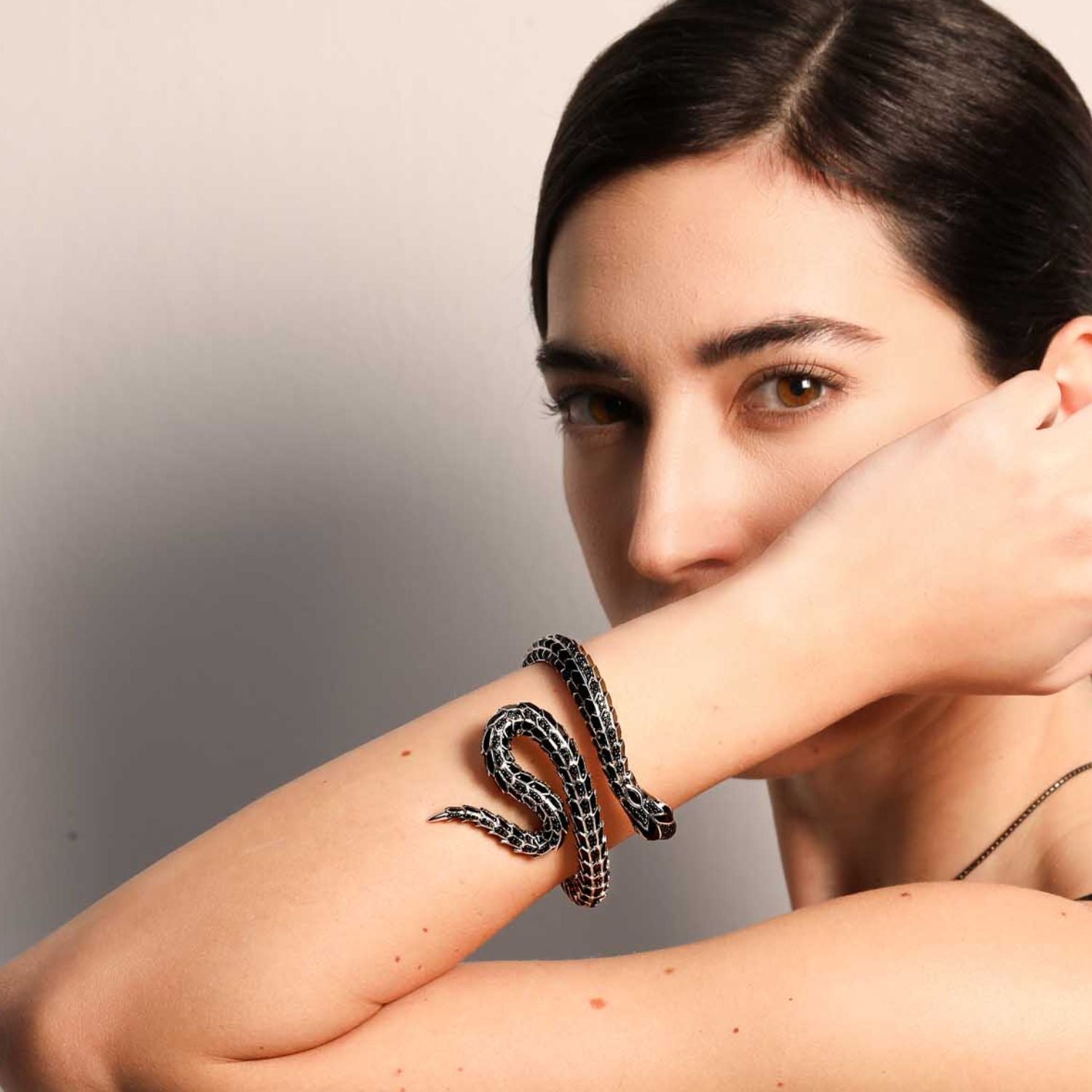 Woman wearing an elegant black and silver Eragon snake bracelet coiled around her forearm, looking directly at the camera against a neutral background.