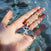 Nessie Fin pendant by Seinerzeit – ocean-inspired sterling silver jewelry with blue and white CZ stones, shaped like a whale tail and photographed in hand in the sea
