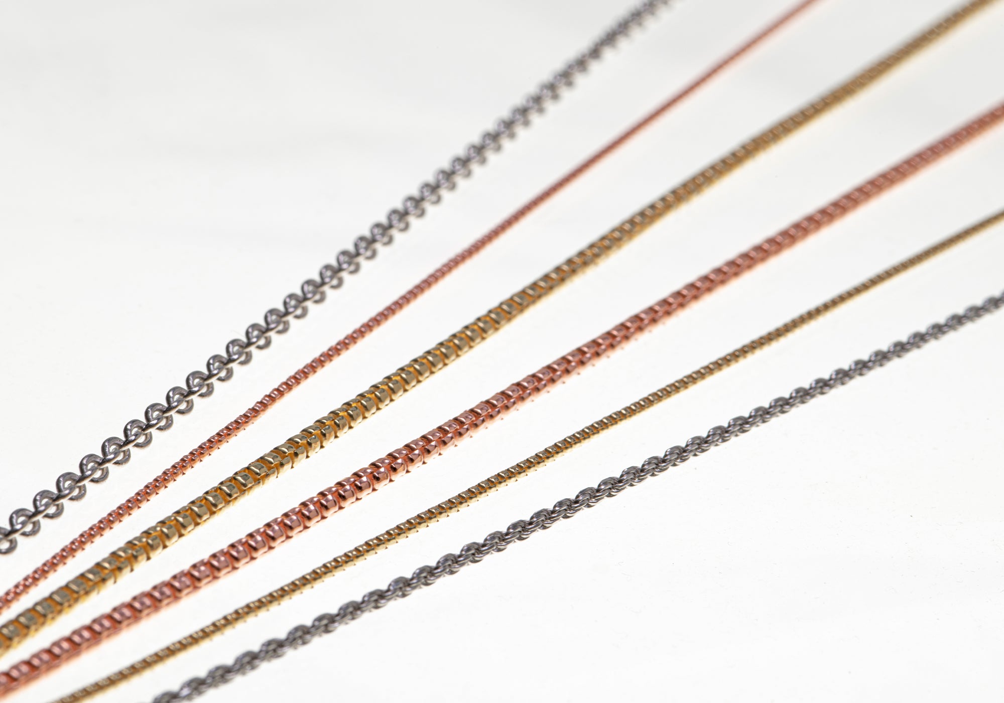 Silberketten von Seinerzeit in Sterling Silber, roségold und gelbgold in Strängen als Stimmungsbild mit weißem Hintergrund.