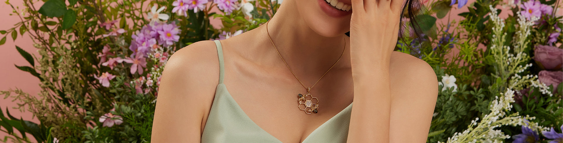 Woman wearing the Seinerzeit Bommel Bee pendant in gold with intricate honeycomb design and two detailed bee motifs, styled against a backdrop of colorful spring flowers