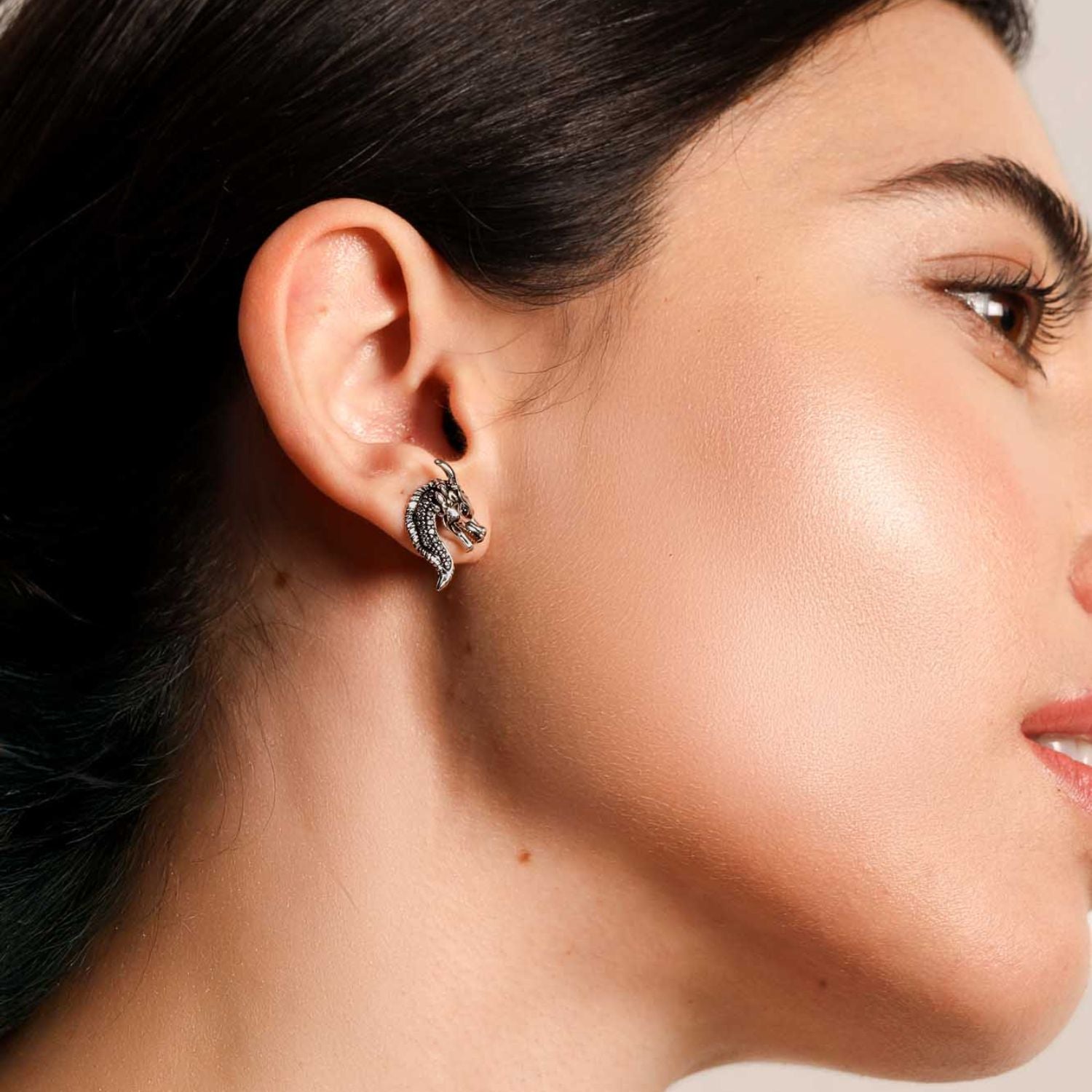 Close-up side profile of a woman wearing the Drakonis dragon stud earring in oxidized silver with intricate scale detailing from Seinerzeit Flora & Fauna