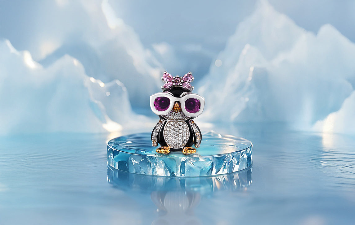 Kiki Penguin pendant in 925 sterling silver with pavé CZ stones, purple sunglasses and pink bow, displayed on ice — Seinerzeit Christmas jewelry.